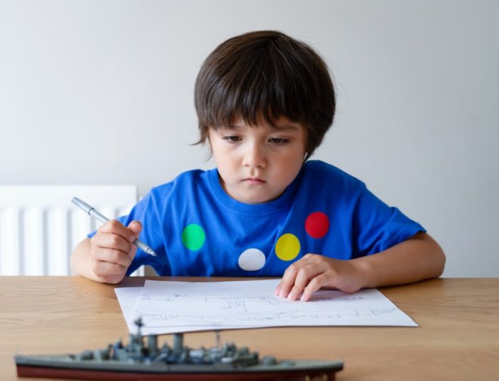 A young boy in blue t-shirt solving common core math problem