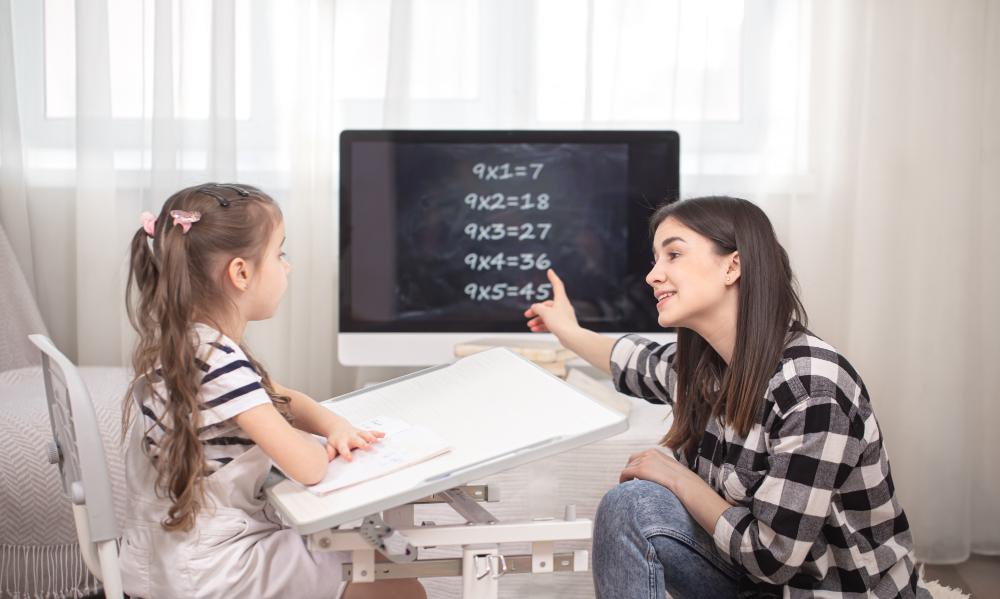 A mother with a child sits at the table and does math homework