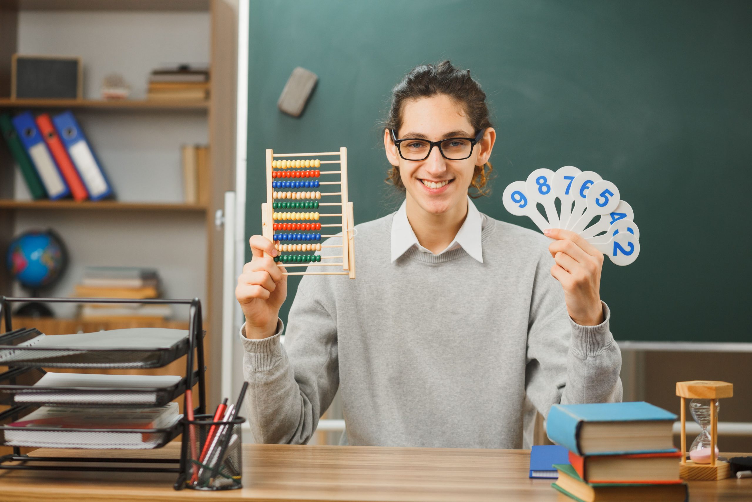 Male Math teacher in glasses with abacus in one hand and number cards in another