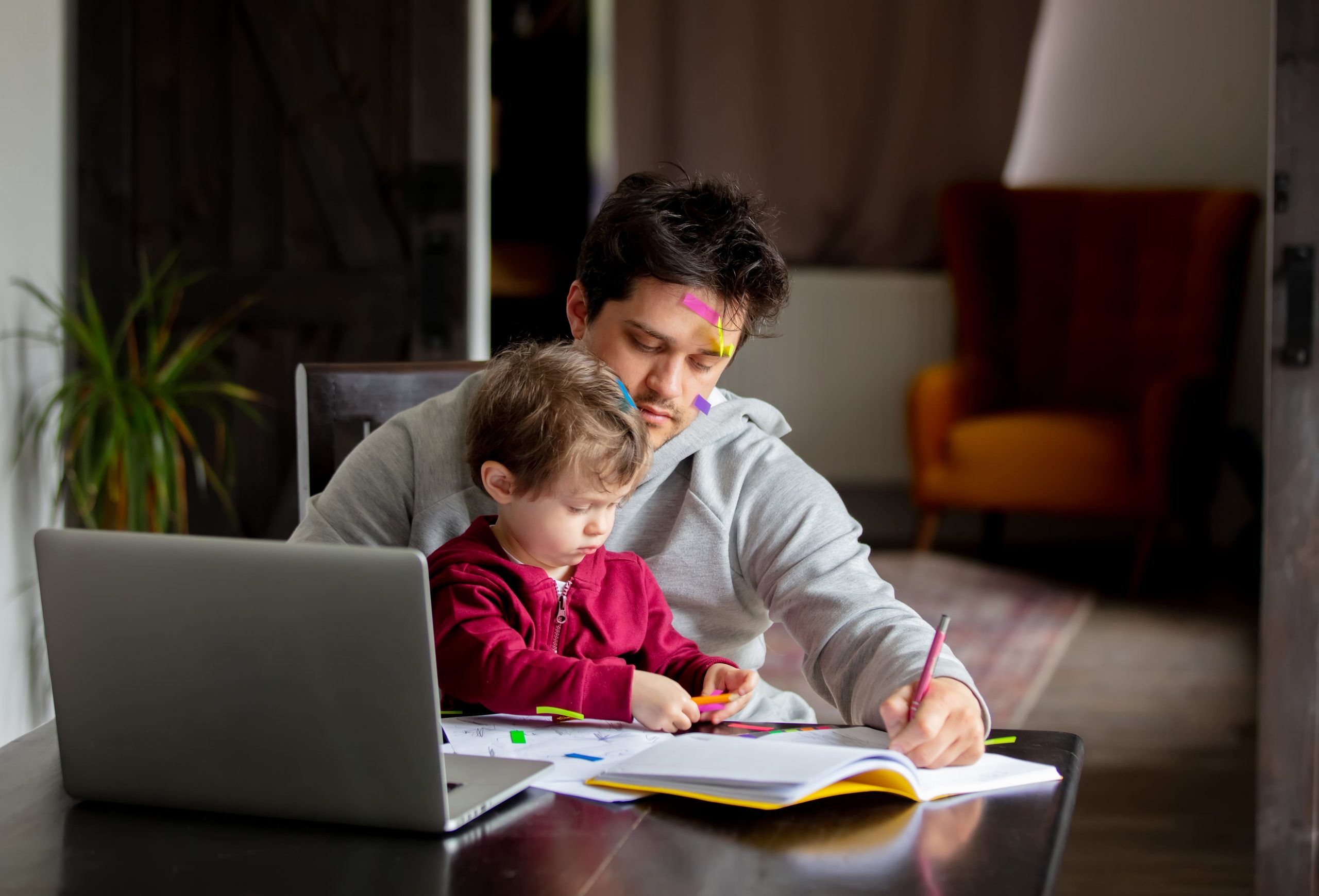 A boy with his father doing homework on a table